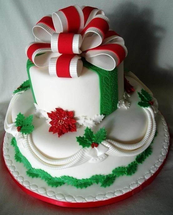 A unique and bold Christmas wedding cake in white, red and green, with colorful leaves, berries and a large bow on top
