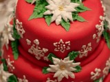 a red Christmas wedding cake decorated with white and green flowers of sugar looks pretty and is done in traditional holiday colors
