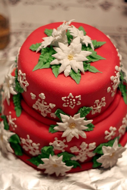 a red Christmas wedding cake decorated with white and green flowers of sugar looks pretty and is done in traditional holiday colors