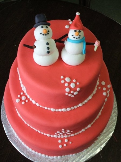 a red Christmas wedding cake with snowballs and funny snowmen toppers is all about winter