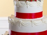 a white wedding cake decorated with red ribbons, with red roses and berries on top is a nice and traditional Christmas dessert