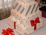 a Christmas wedding cake in red, white and silver composed as if it’s made of gift boxes and topped with red bows