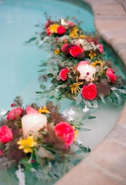 bold florals with greenery and dark foliage and candles floating in the pool look amazing and very unusual
