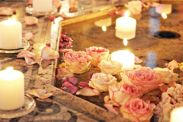 A pool with floating pink and white roses and candles looks magical and very beautiful and charms with romance