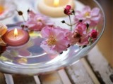 a glass bowl with floating candles and pink blooms is a beautiful wedding centerpiece or decoration