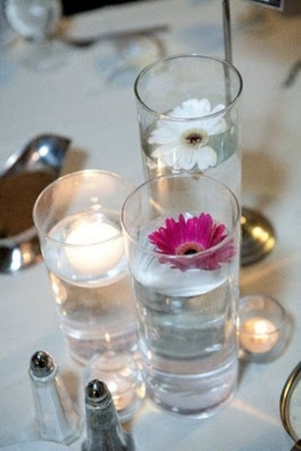 tall glasses with floating blooms and a candle is a pretty and easy cluster wedding centerpiece to try