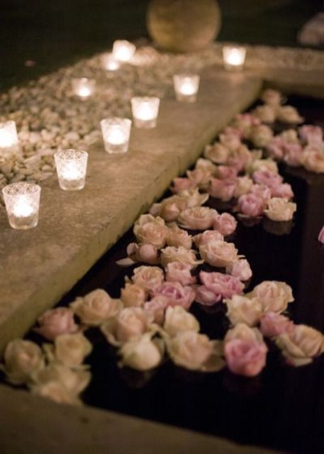 a small outdoor pool with floating pink roses and candles lining up the edge is a stylish and beautiful idea to rock