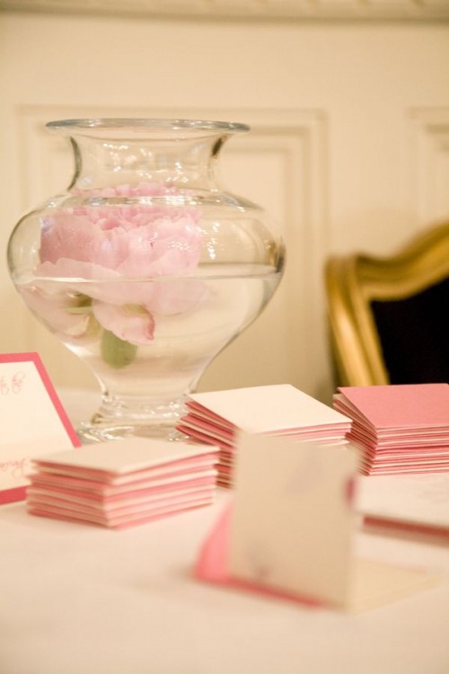 a large vase with a pink peony floating inside is a lovely idea for any wedding and won't break the bank