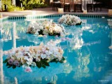 white and pink floral arrangements with greenery floating in the pool are a lovely and beautiful idea to style it for a wedding