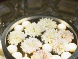 a stone bowl with floating white blooms and candles is a chic and pretty decoration for both indoors and outdoors