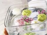 a clear bowl with floating bold blooms and candles is a lovely way to create a centerpiece without applying much effort