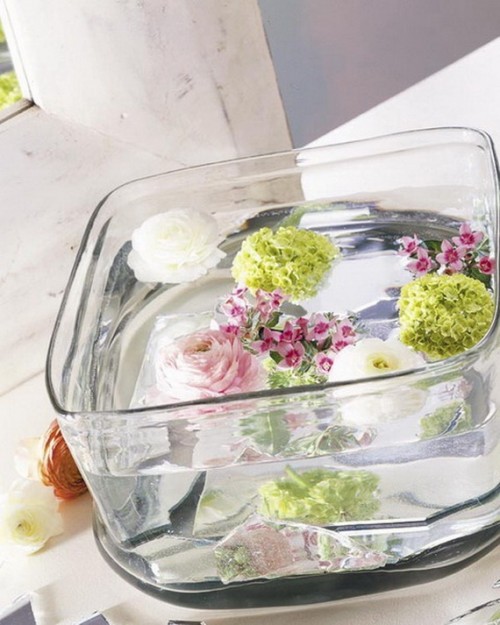 a clear bowl with floating bold blooms and candles is a lovely way to create a centerpiece without applying much effort