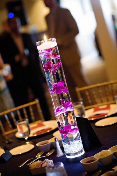a tall glass vase with floating hot pink blooms and a floating candle on top is a lovely idea to add to the decor