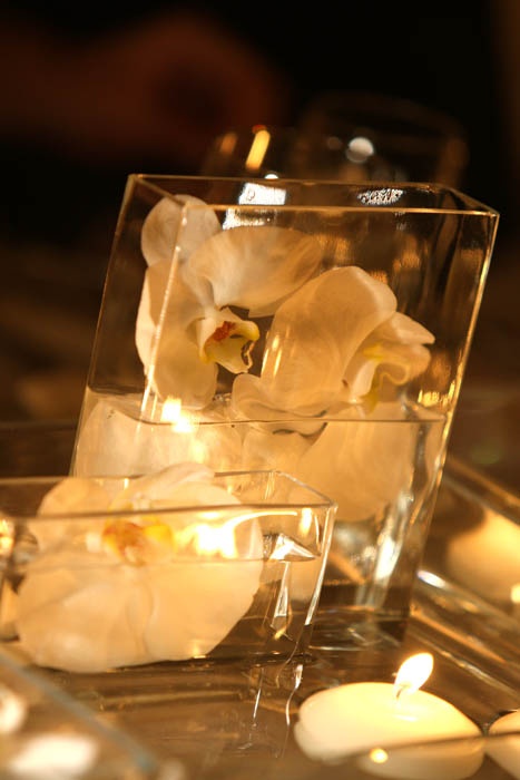 square vases with floating white orchids and vases with floating candles is a pretty and refined wedding centerpiece
