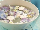 a bowl with lilac blooms and floating candles is a stylish idea for any wedding, for an outdoor or indoor one