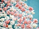 a pool with floating white and pink roses looks romantic and very wedding-ready