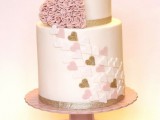 a neutral wedding cake with gold stripes, a blush cream hearts and more hearts decorating the cake