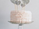 a blush ruffle wedding cake topped with silver glitter hearts is a tender and sweet idea for Valentine’s Day