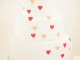 a white wedding cake decorated with red and pink hearts is a lovely and bright idea for a Valentine wedding