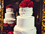 a plain and ruffle white wedding cake topped with red roses looks spectacular and bold and brings traditional romance