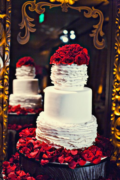 a plain and ruffle white wedding cake topped with red roses looks spectacular and bold and brings traditional romance