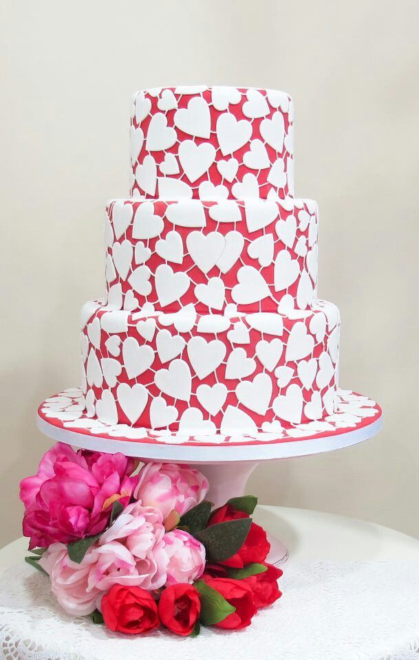 a pink wedding cake with hearts covering the whole piece is a fun and cheerful idea for a modern Valentine wedding