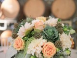 a swete vineyard wedding centerpiece of neutral and coral blooms, greenery, berries and a cabbage is a nice option for a rustic wedding, too