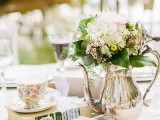 an elegant vintage wedding centerpiece of a silver tea pot and milker, neutral blooms and a floral cup for a vintage vineyard wedding