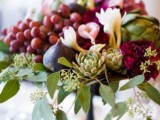 a bright vineyard wedding centerpiece of greenery, neutral blooms, grapes and figs is perfect for fall