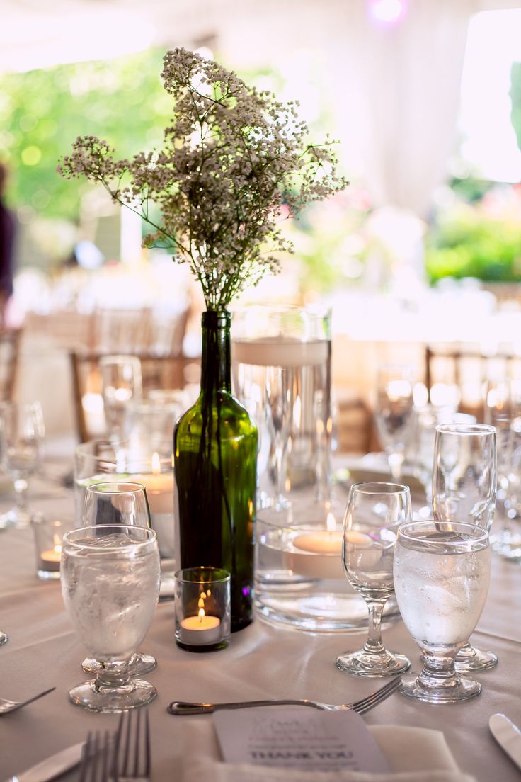 A wine bottle with baby's breath and a candle is a nice idea of a centerpiece for a vineyard wedding