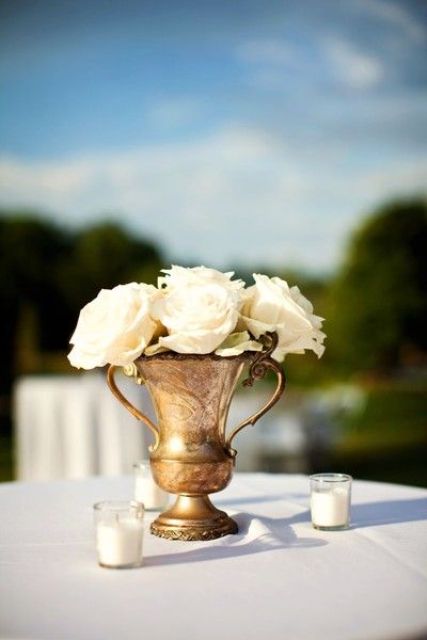 a vintage vase with white roses is a romantic and chic centerpiece that will fit not only a vineyard but many other weddings, too