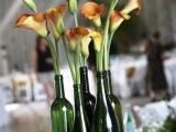 moss, beer bottles and orange callas for a quiry and catchy wedding centerpiece