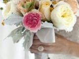 a neutral wedding bouquet of ivory and blush blooms with a single hot pink flower plus pale greenery and berries