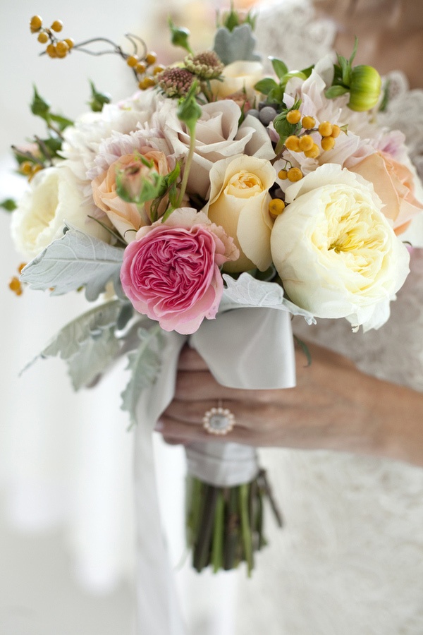 a neutral wedding bouquet of ivory and blush blooms with a single hot pink flower plus pale greenery and berries