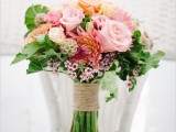 a colorful wedding bouquet in pink, red, yellow and with greenery for a texture plus a rustic wrap