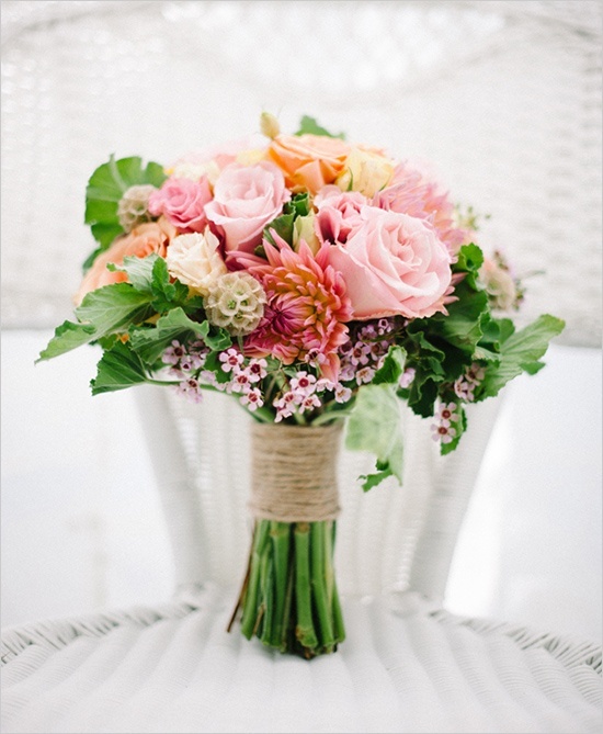 a colorful wedding bouquet in pink, red, yellow and with greenery for a texture plus a rustic wrap