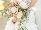 a romantic cascading wedding bouquet with king proteas, greenery and white blooms for a statement