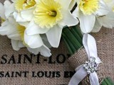 a simple and rustic wedding bouquet of white daffodils with a burlap wrap and a glam rhinestone bow