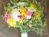 a spring wedding bouquet of white, pink and yellow blooms, greenery and wildflowers