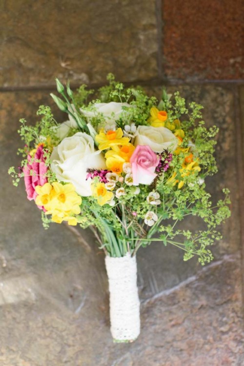 a spring wedding bouquet of white, pink and yellow blooms, greenery and wildflowers
