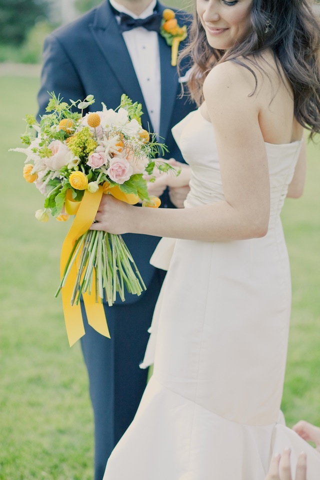 a romantic spring wedding bouquet of blush peonies and craspedia plus yellow ribbons