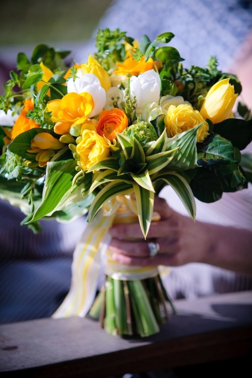 a colorful spring wedding bouquet in marigold and white, with plenty of foliage for a texture