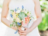 a cute spring-like wedding bouquet in blue, peachy, marigold and with greenery and succulents