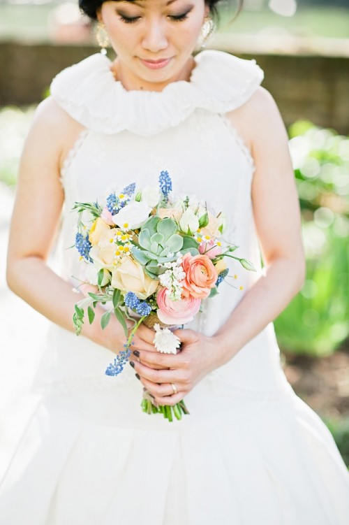 a cute spring-like wedding bouquet in blue, peachy, marigold and with greenery and succulents