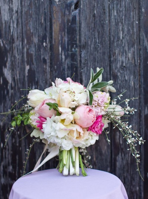 a pastel wedding bouquet with blush, white and hot pink blooms, greenery and some texture with blooming branches