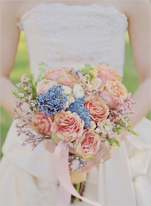 a spring wedding bouquet of peachy blooms, some blues and blooming branches for a romantic feel