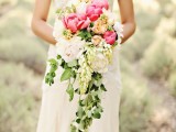 a cascading wedding bouquet of neutral and bright pink blooms with greenery down is a trendy idea with a rustic feel