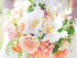 a bright spring wedding bouquet with peachy, pink and white blooms, greenery and daisies