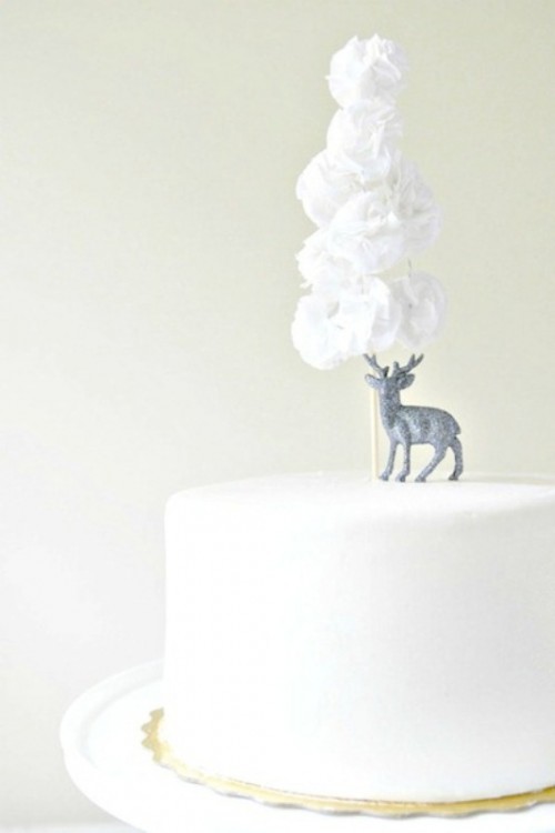 a simple white wedding cake topped with a deer and white fabric blooms is a beautiful winter solution
