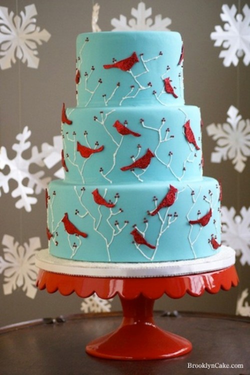 a blue wedding cake with white branches and red birds is a cool and bold idea for a bright winter wedding